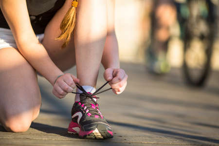 Girl is tying close-up the laces sports shoe before running. Running, healthy lifestyle.の写真素材