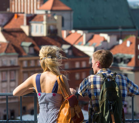 Young couple of tourists looking at the Old European Town from the observation tower, old architecture in the blur in the background.の写真素材
