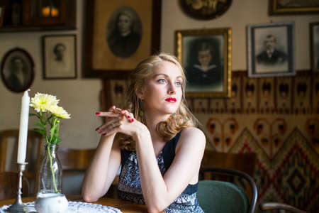 Young beautiful retro woman sitting at a table.の写真素材