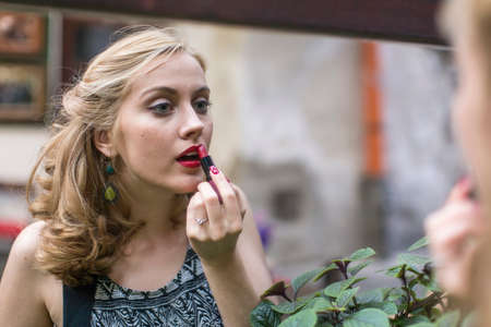 Beautiful young woman wearing lipstick near the mirror.の写真素材