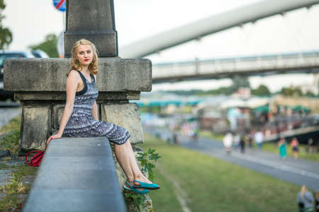 Beautiful young lady sits on the quay Vistula river in Krakow.の写真素材