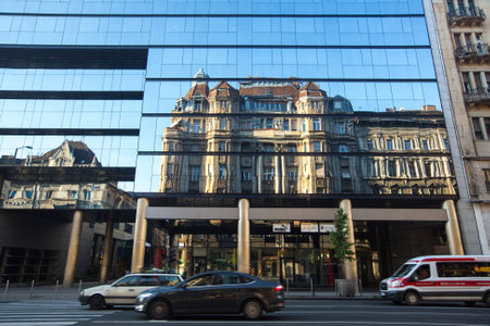 BUDAPEST, HUNGARY - SEPT 20, 2015: Traffic on the street in the historic centre of Budapest. The reflection of the ancient building in the Windows of a modern building.のeditorial素材