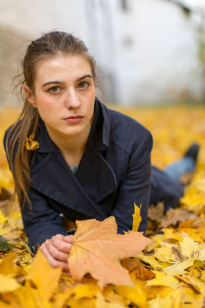 Portrait of young girl lying in fallen leaves.の写真素材