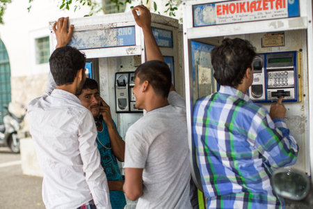 KOS, GREECE - SEP 28, 2015: Refugees talking on a phone. Kos island is located just 4 km. from the Turkish coast, and many refugees come from Turkey in an inflatable boats.のeditorial素材