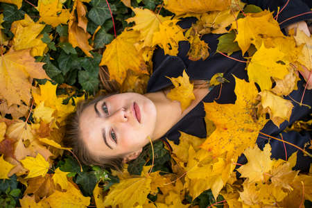 Young girl in autumn park. Portrait on fallen leaves.