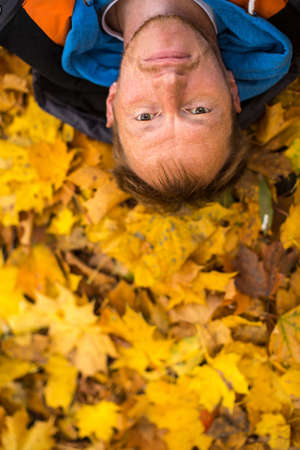 Young man lying on yellow leaves.の写真素材