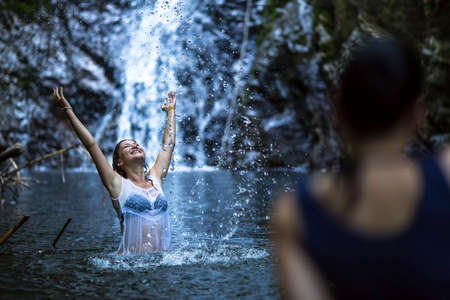An attractive young woman bathing near the waterfall.の写真素材