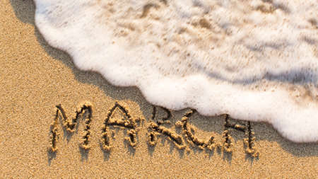 Inscription MARCH on a gentle beach sand with the soft wave (months of the year series)の写真素材