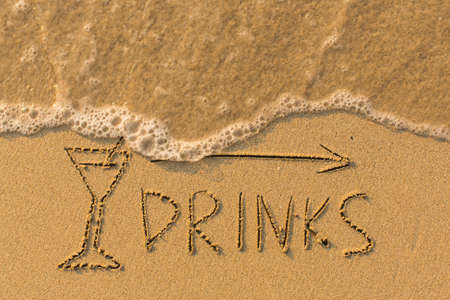 Word Drinks and arrow drawn on the sand of a beach with the soft wave.の写真素材