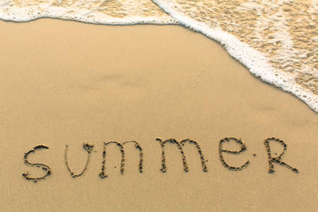 Summer - word drawn on the sand beach with the soft wave.の写真素材