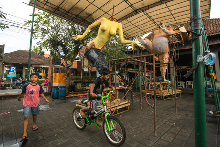 UBUD, INDONESIA - MAR 5, 2016: Unidentified local children during built Ogoh-ogoh are statues for the Ngrupuk parade, which takes place on eve of Nyepi day. Nyepi is a public holiday in Indonesia.のeditorial素材