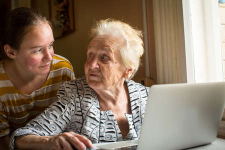 Young girl teaches her grandmother to use a computer.