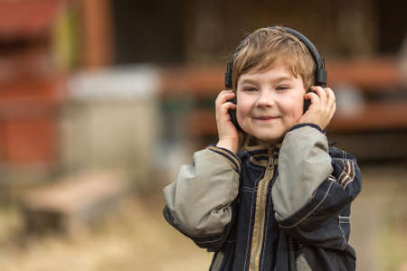 Little boy listening to music on headphones in the street, closeup portrait.の写真素材