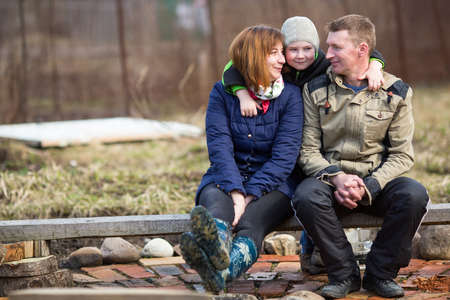 Young married couple with a young son sitting outdoors.