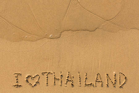 I Love Thailand - text written on sandy beach with the soft wave.
