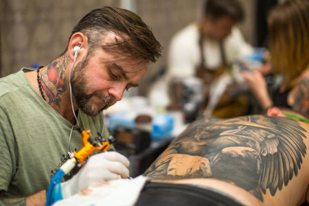 KRAKOW, POLAND - JUNE 11, 2016: Unidentified festival participant make a tattoos at the 11-th International Tattoo Convention in the Congress-EXPO Center of Krakow.のeditorial素材