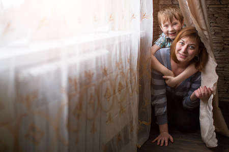 Young mother playing with her little son in the room.の写真素材