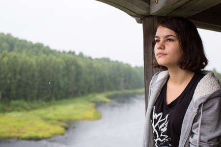 Young girl from the hill looking at the river and the forest.の写真素材