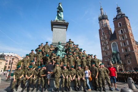 KRAKOW, POLAND - FEB 11, 2016: Polish soldiers in the free day posing at the camera near Adam Mickiewicz Monument at the Main Market Square, St.Mary Cathedral in the background.のeditorial素材