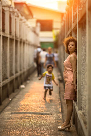 Young Asian woman standing at the wall in the alley.の写真素材