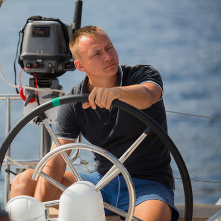 Man sits at the helm on the boat. Sailing ship during sea yacht race.の写真素材