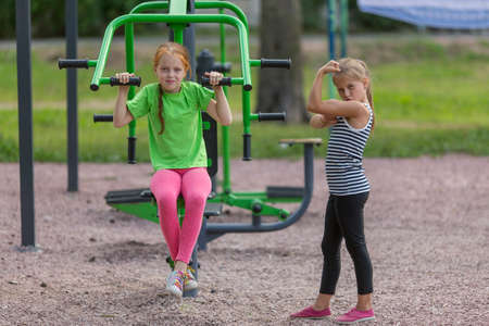 Two cute girls on the equipment for exercise in the Park.の写真素材