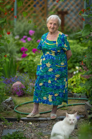 An elderly woman stands in her garden.の写真素材