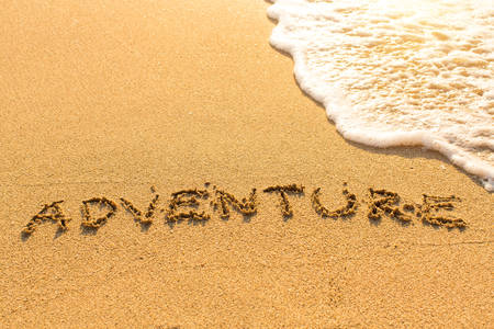 Adventure - inscription on sand beach with the soft wave.の写真素材