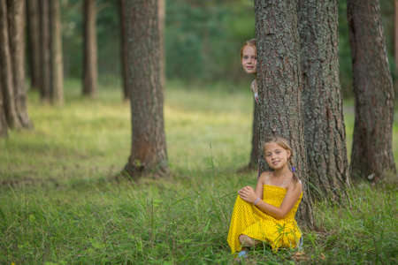 Two little girls pose for the camera among the pines in the Park.の写真素材