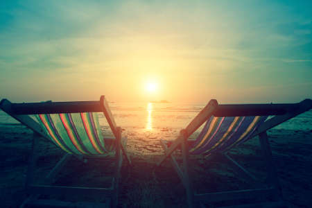 A couple of deck chairs at dusk on sea beach.の写真素材
