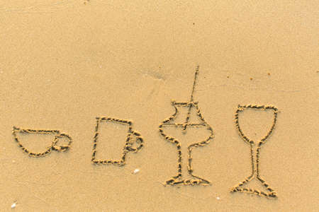 Glasses and crockery are drawn in the beach sand.の写真素材