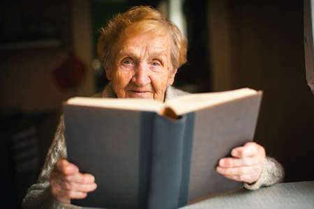 Portrait of elderly woman reading a book.の写真素材