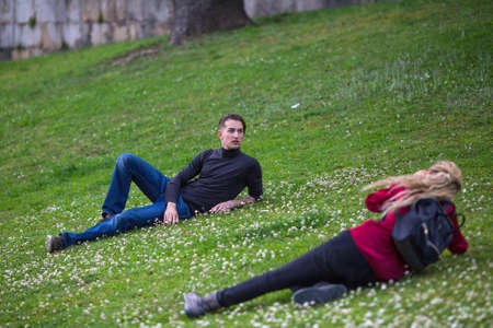 Young guy posing for a female photographer lying in the meadow.の写真素材