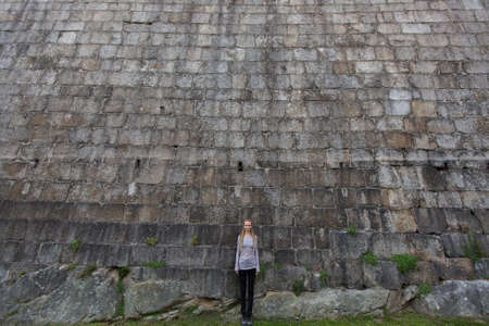 Girl standing near the a huge stone wall.の写真素材
