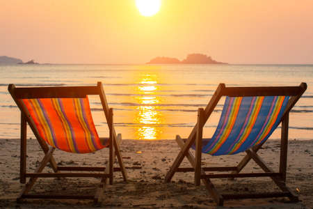 Couple of sun loungers on the beach during sunset.の写真素材