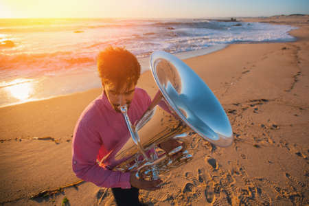 Young musician playing the trumpet on the sea coast. の写真素材
