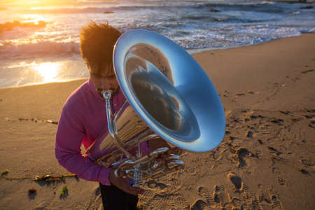 Musician playing the Tuba on the sea coast during an amazing sunset.の写真素材