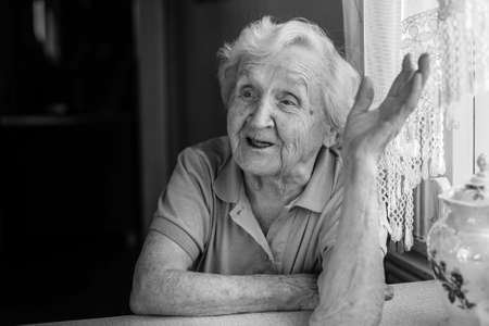Black-and-white portrait of an elderly woman emotional says in her home.の写真素材