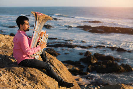 Musician play to musical instrument Tuba on romantic sea shore.の写真素材