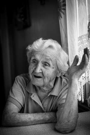 Black and white portrait of an old woman talking in the house.の写真素材