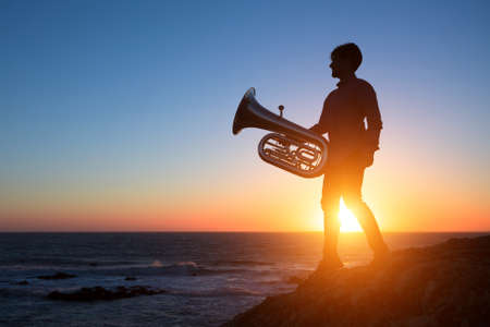Silhouette of musician with Tuba on sea shore at sunset .の写真素材