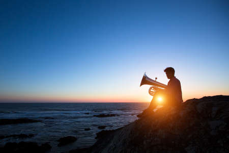 Silhouette of musician play Tuba on sea shore at sunset .の写真素材