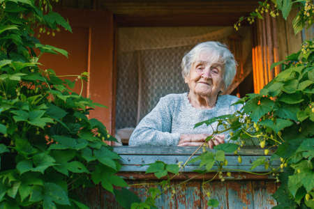 Elderly woman on a green terrace in his rural house.の写真素材