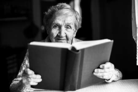Portrait of an elderly woman reading a book. Black-and-white picture.の写真素材