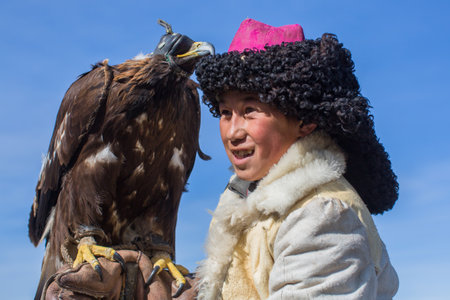 BAYAN-ULGII, MONGOLIA - SEP 30, 2017: Kazakh Eagle Hunter traditional clothing, while hunting to the hare holding a golden eagle on his arm in desert mountain of Western Mongolia.のeditorial素材