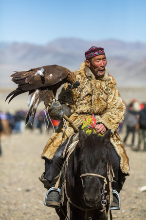 OLGIY, MONGOLIA - SEP 30, 2017: Kazakh Golden Eagle Hunter at traditional clothing, with a golden eagle on his arm during annual national competition with birds of prey "Berkutchi" of West Mongolia.のeditorial素材