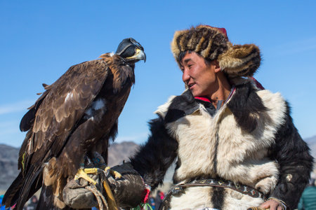 OLGIY, MONGOLIA - SEP 30, 2017: Kazakh Golden Eagle Hunter at traditional clothing, with a golden eagle on his arm during annual national competition with birds of prey "Berkutchi" of West Mongolia.のeditorial素材