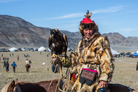 OLGIY, MONGOLIA - SEP 30, 2017: Kazakh Golden Eagle Hunter at traditional clothing, with a golden eagle on his arm during annual national competition with birds of prey "Berkutchi" of West Mongolia.のeditorial素材