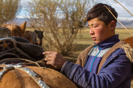 BAYAN-OLGII, MONGOLIA - SEP 28, 2017: Kazakh Berkutchi (Eagle hunter) do saddles horse. In Bayan-Olgii Province is populated to 88,7% by Kazakhs.のeditorial素材