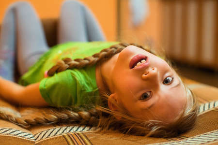 Portrait of a five year old girl lying on the sofa.の写真素材